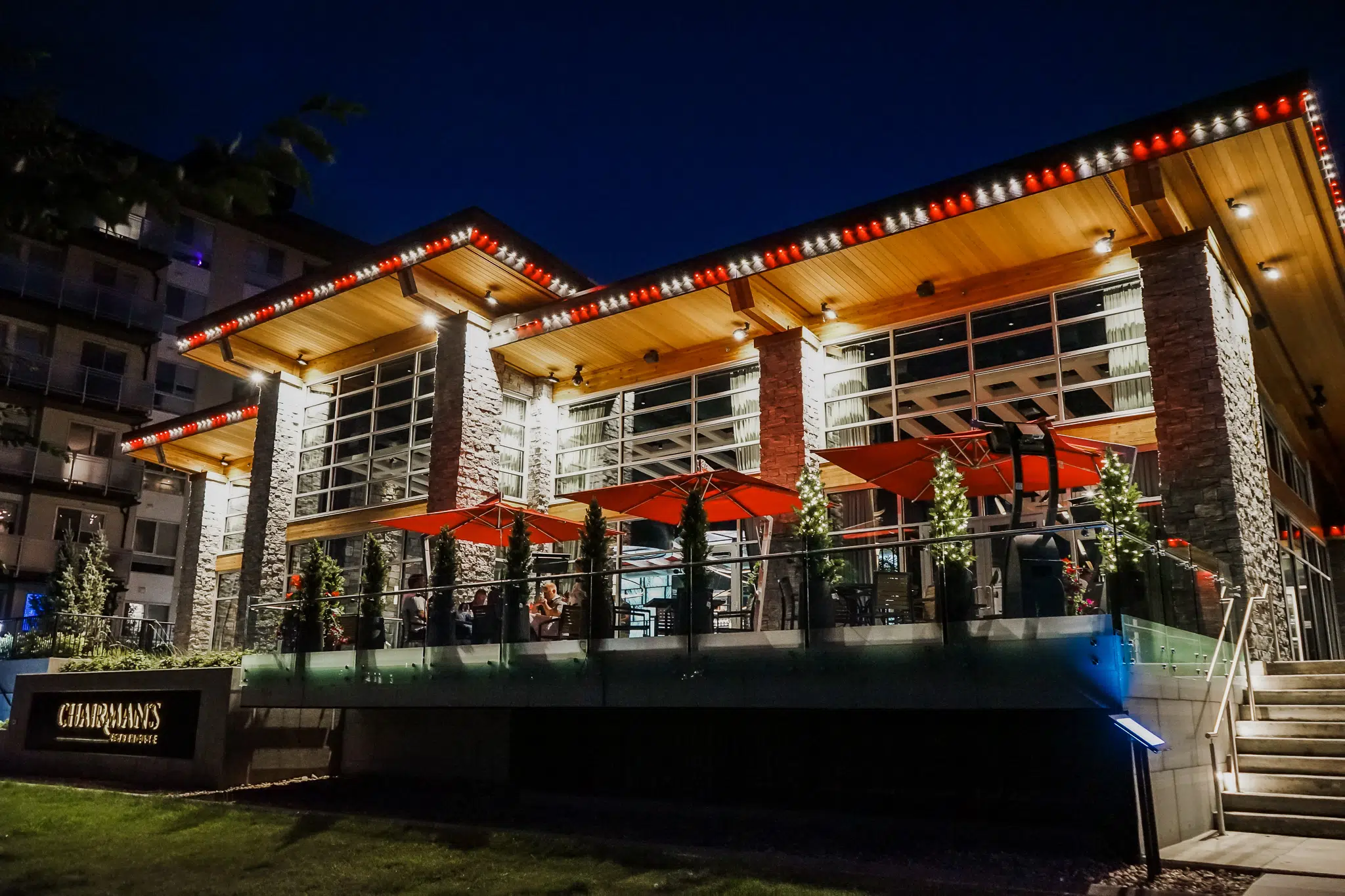 A modern restaurant glows warmly at night with vibrant outdoor seating