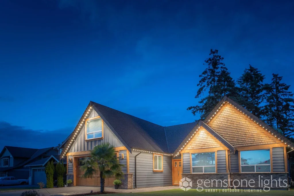 A cozy house is beautifully outlined with warm string lights against a twilight sky