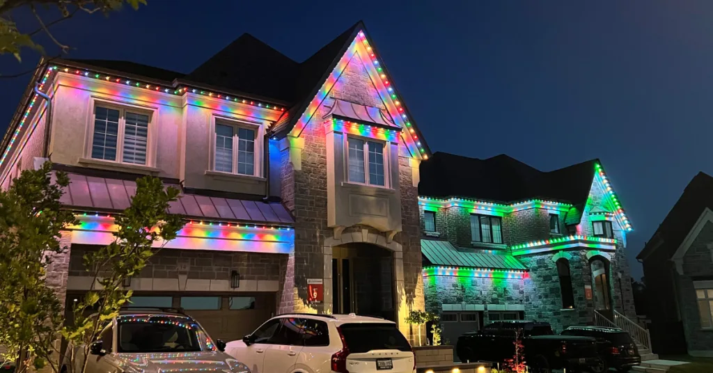 A large house is illuminated with colorful festive lights at dusk