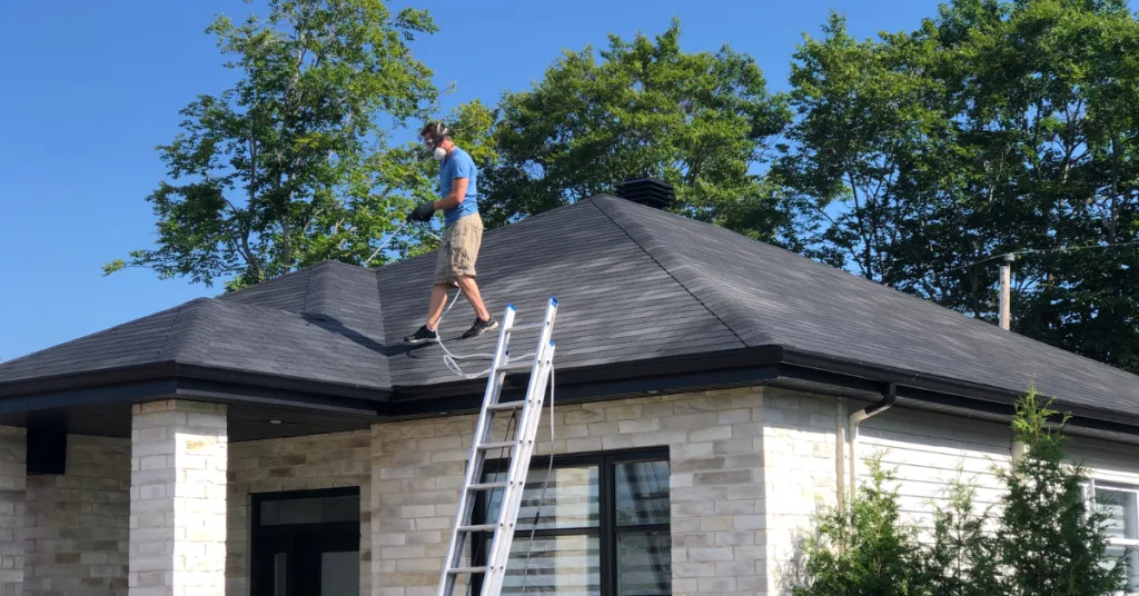 A person is working on a rooftop while balancing on a ladder