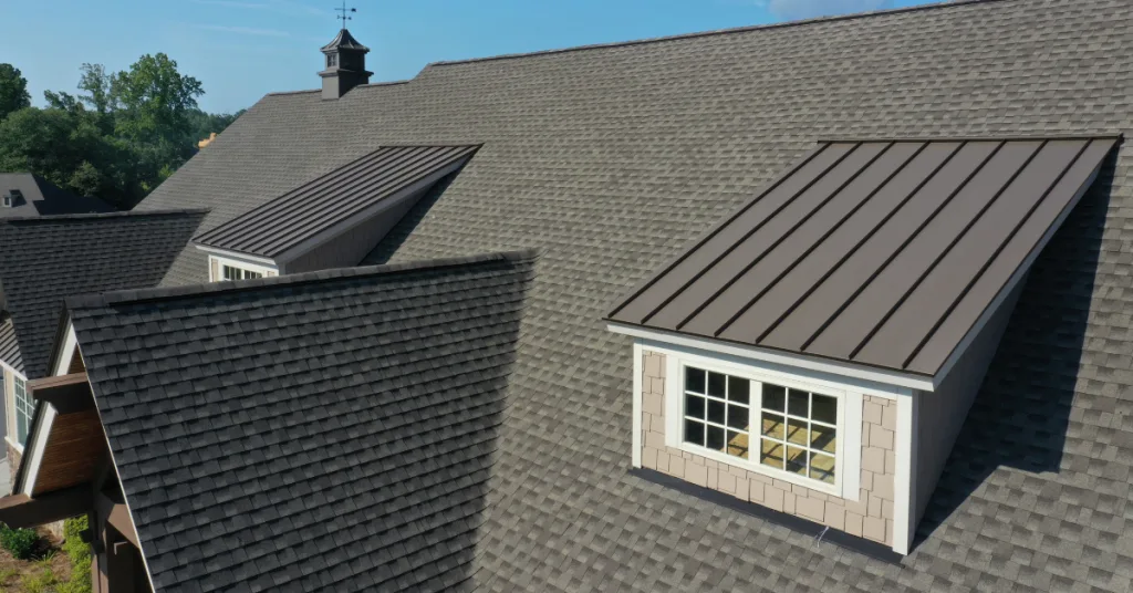 A sloped roof features two dormer windows under a clear blue sky