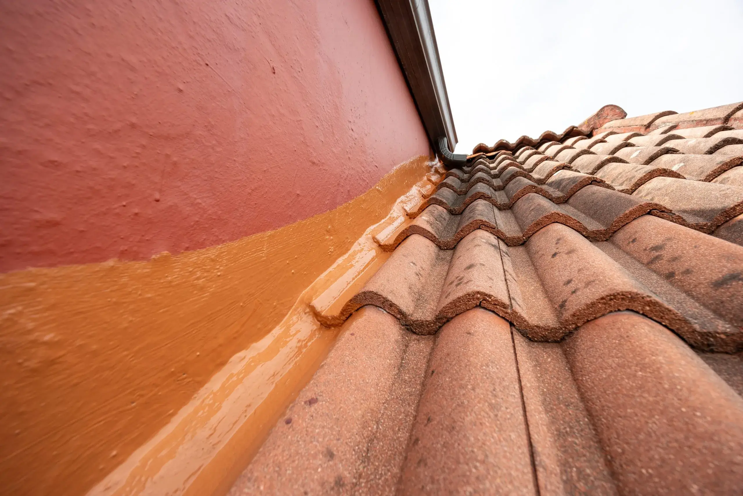 A diagonal view of textured roof tiles meeting a painted wall