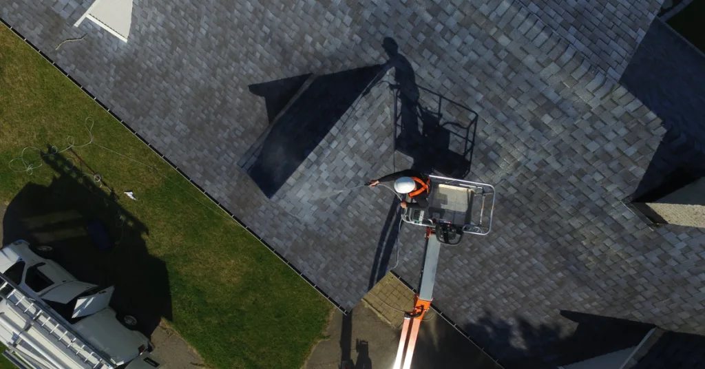 A worker in a lift inspects or repairs a roof from above